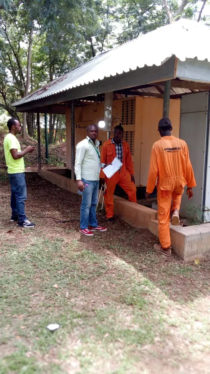 Engineers and client staff inspecting outdoor equipment enclosures under a shelter