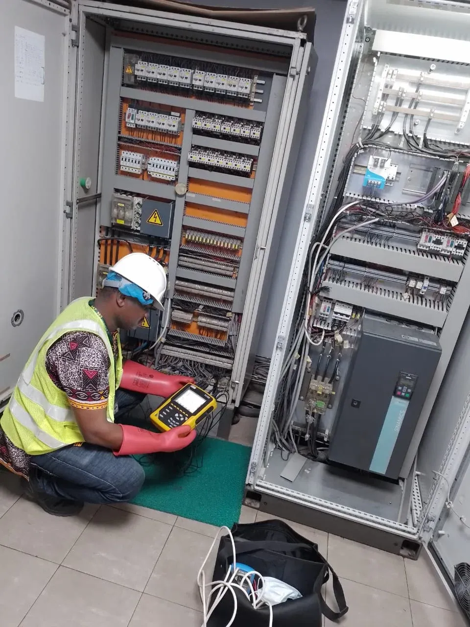 Remotec engineer in PPE testing a variable-speed drive panel with a power quality analyser