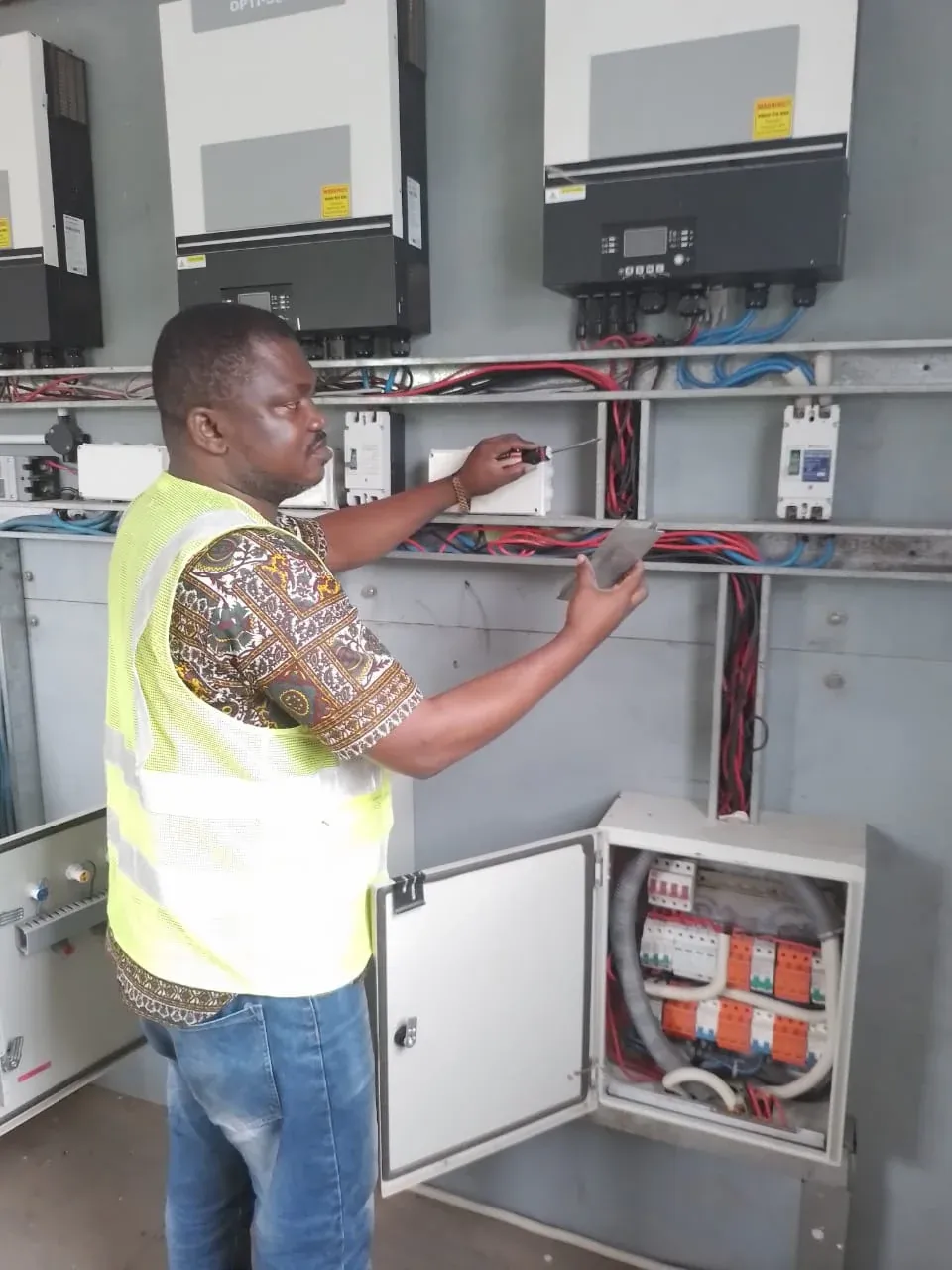 Engineer working on inverters and DC distribution boards in a solar power room