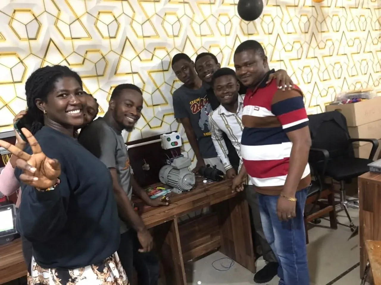 Group of trainees smiling beside motor training rigs after a workshop session